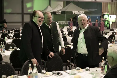 Karl-Heinz Welz, Andreas Loewel und Peter-Josef Paffen stehen und unterhalten sich an einer gedeckten Tafel, hinter ihnen stehen weitere gedeckte Tafeln und 3 Pavillons mit weißem Fendt Logo.