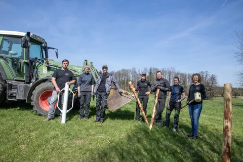 7 Personen, davon 3 Männer stehen vor einem grünen Fendt Traktor (links) und schauen in die Kamera