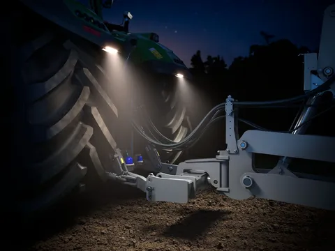Das Heck eines grünen Fendt 1000 Vario in einer Halle fotografiert, die Deichselbeleuchtung GroundVision an den Kotflügeln ist eingeschaltet.