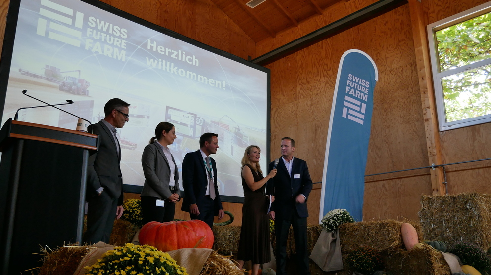 Besucher sitzen in einer Halle und schauen sich die Eröffnung der Swiss Future Farm an
