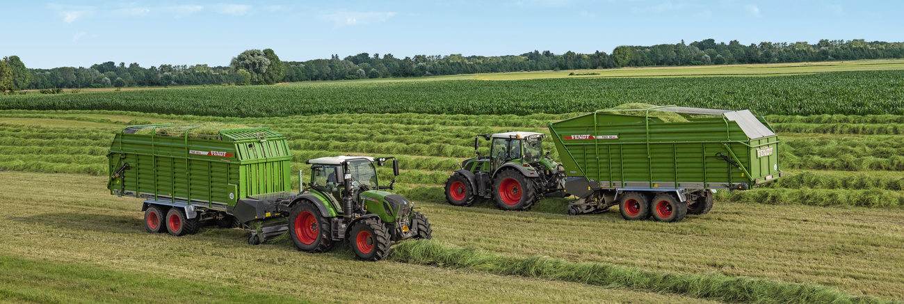 Zwei Fendt Tigo MR Ladewagen mit Fendt Traktoren auf einer Wiese