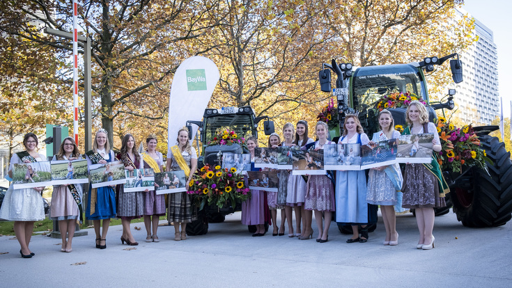 Die Damen mit ihren Kalendern neben mit Blumen geschmückten Fendt Traktoren