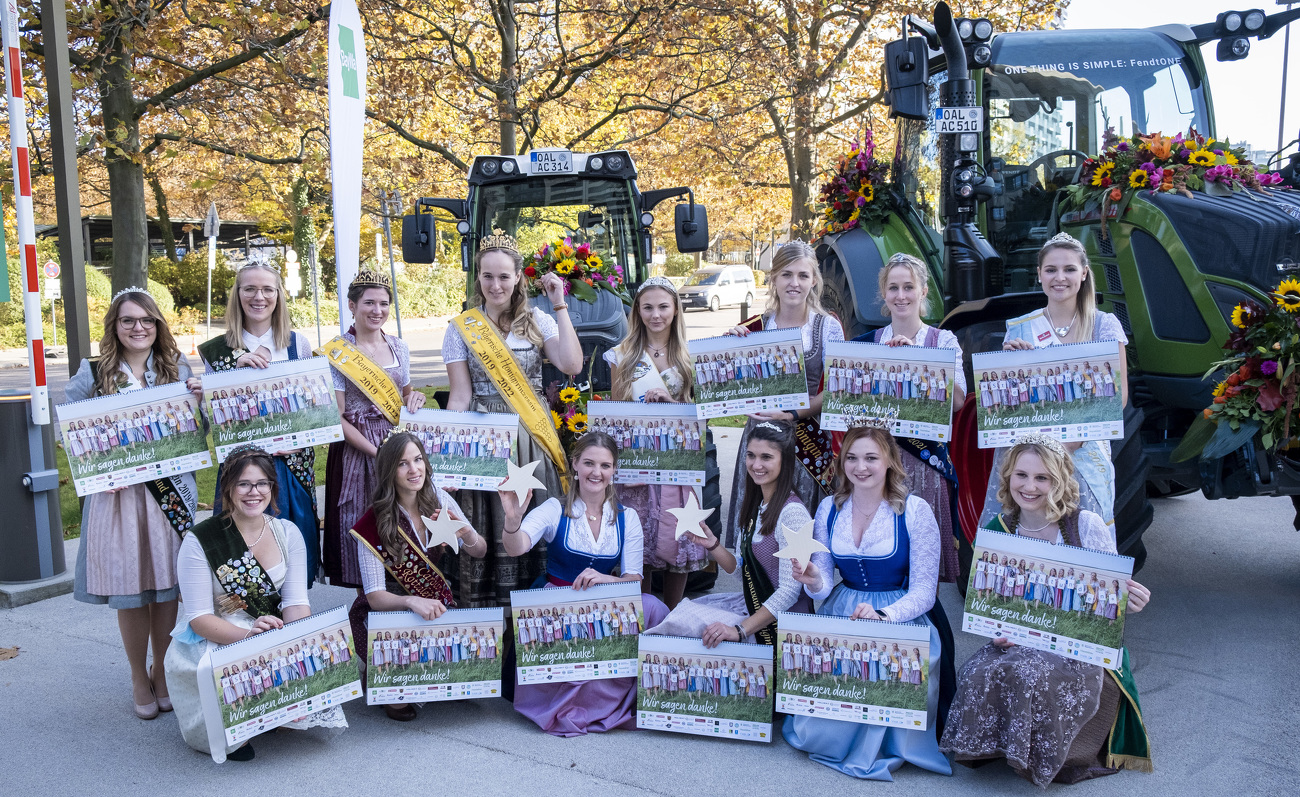 Die Damen mit ihren Kalendern neben mit Blumen geschmückten Fendt Traktoren