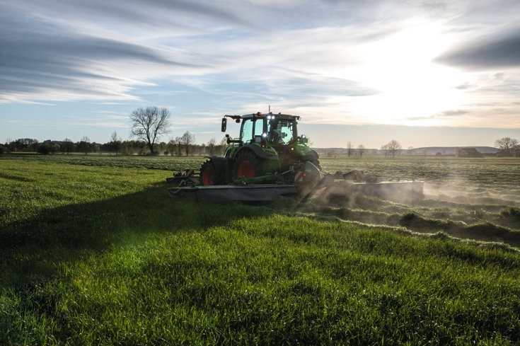 Fendt Traktor mit Slicer Mähwerk im grünen Feld