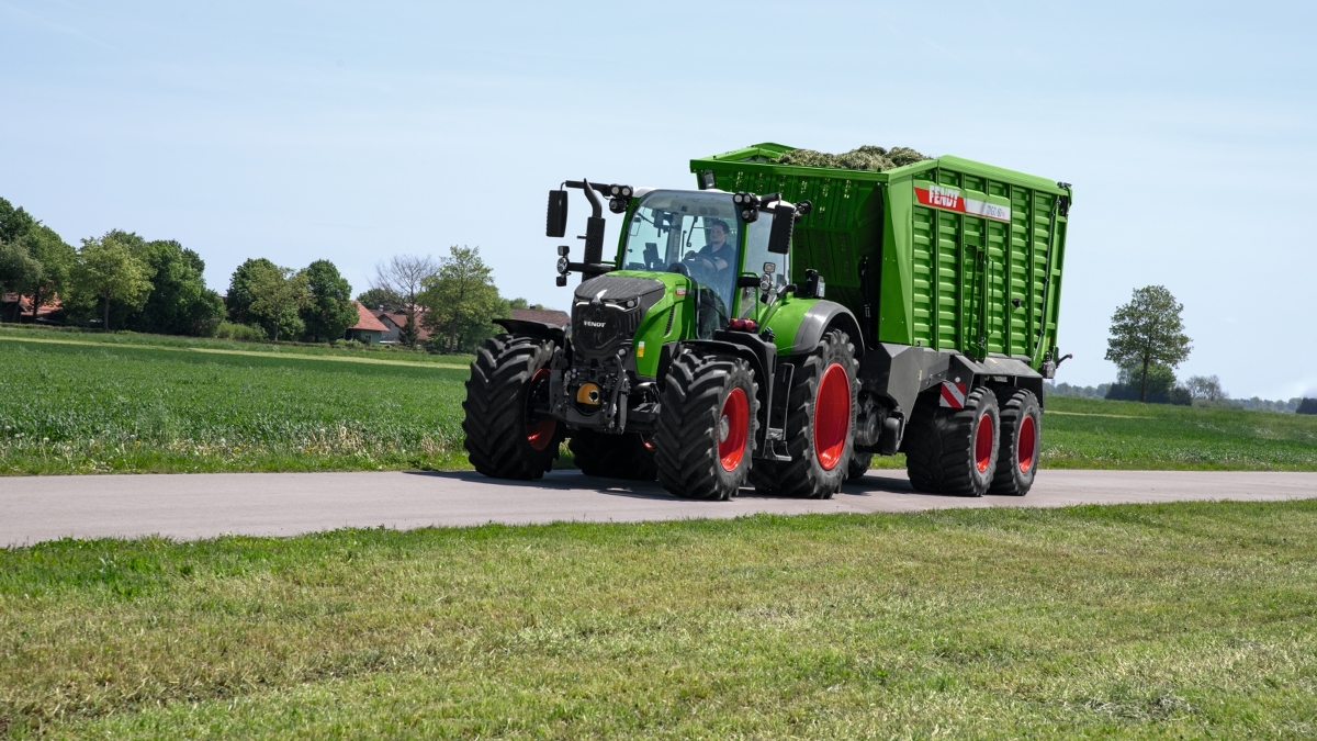 Ein Landwirt fährt mit einem Fendt 700 Vario Gen7 Traktor und einem Fendt Tigo Ladewagen auf der Straße.