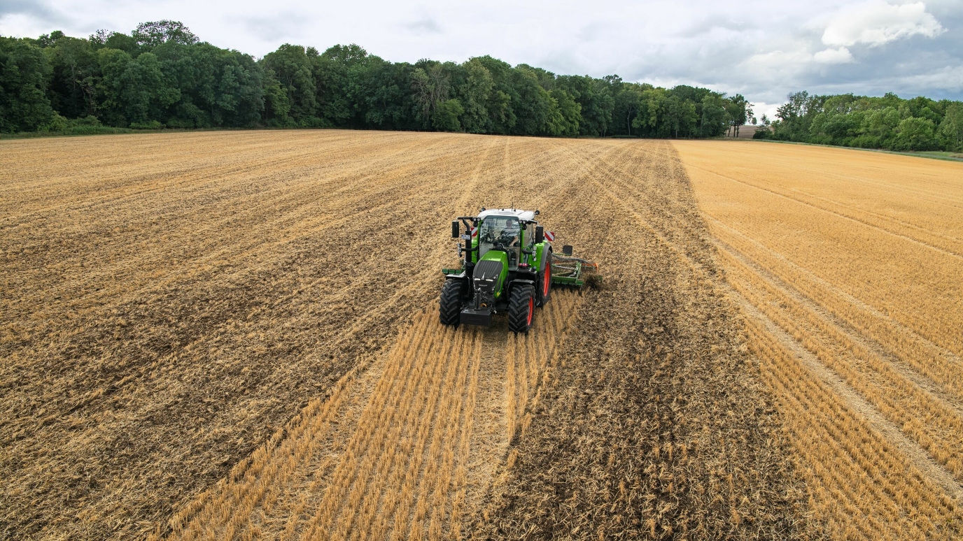 Ein grüner Fendt Traktor mit roten Felgen bei der Bodenbearbeitung auf dem Feld fährt die Spurführung A+ Winkel