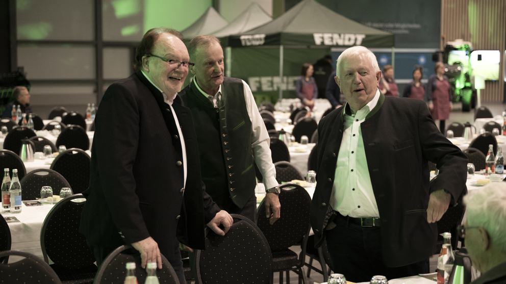 (v.l.) Karl-Heinz Welz, Andreas Loewel und Peter-Josef Paffen auf der Fendt Ehemaligenfeier 2025 im Fendt Forum Karl-Heinz Welz, Andreas Loewel und Peter-Josef Paffen stehen und unterhalten sich an einer gedeckten Tafel, hinter ihnen stehen weitere gedeckte Tafeln und 3 Pavillons mit weißem Fendt Logo.