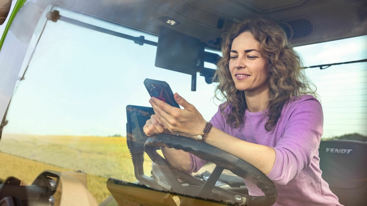 Eine Landwirtin im grünen Fendt Traktor verwendet die Fendt App Parts Books to go
