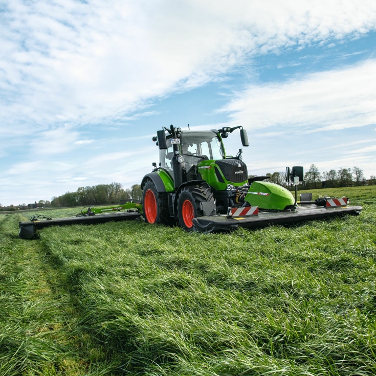 Fendt Traktor fährt mit einem Fendt Slicer Front- und Heckmähwerk auf dem Feld