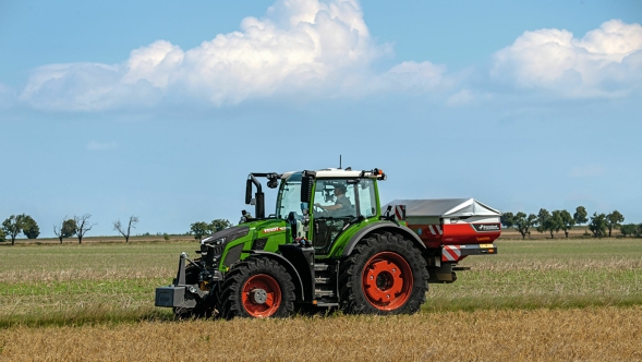 Der grüne Traktor Fendt 600 Vario mit roten Felgen in seitlicher Ansicht auf einer grünen Wiese. Ein blauer Himmerl mit weißen Wolken ist im Hintergrund zu sehen.