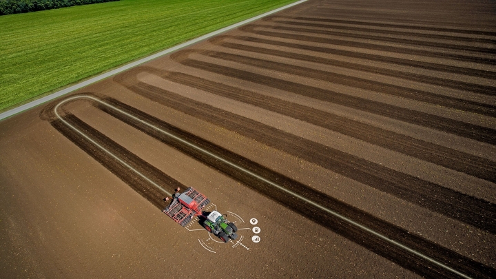 Ein Traktor fährt über einen Acker, dabei ist die präzise Spurführungslinie zu sehen.