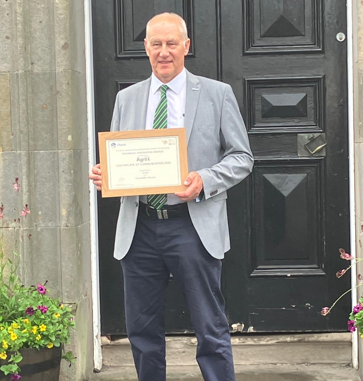 Ein Mann hält eine Urkunde in den Händen und steht vor einer schwarzen Tür