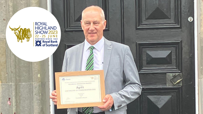 Ein Mann hält eine Urkunde in den Händen und steht vor einer schwarzen Tür