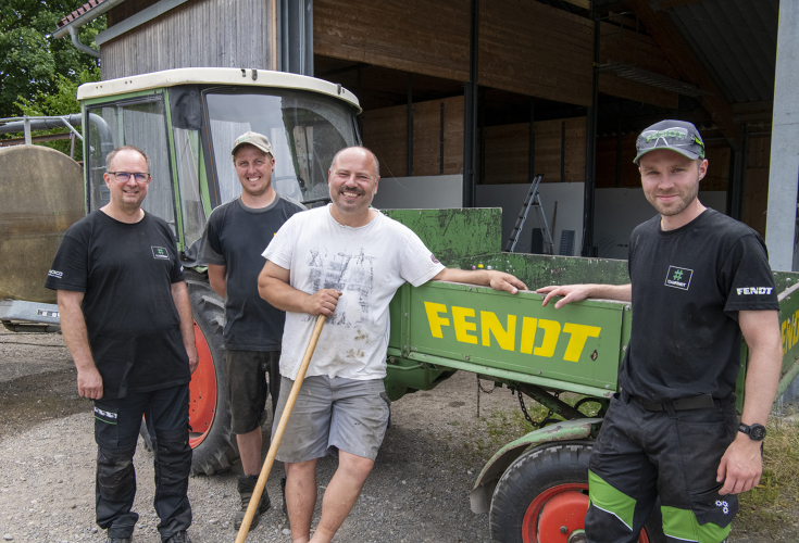 4 Männer stehen lächelnd vor einer grünen Maschine mit gelbem Fendt Schriftzug