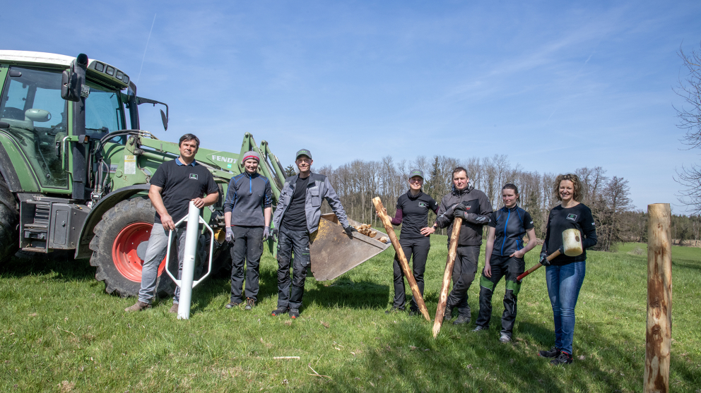 7 Personen, davon 3 Männer stehen vor einem grünen Fendt Traktor (links) und schauen in die Kamera