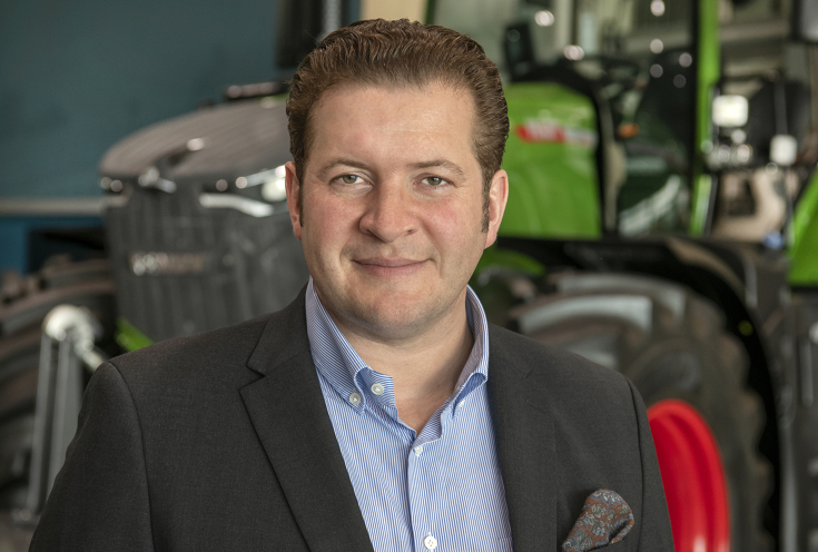 Portrait von Dr. Dominic Esser vor einem Fendt Traktor