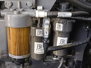 Nahaufnahme des Kraftstofffilters im Fendt 900 Vario MT, klar sichtbar montiert und für Wartungsarbeiten leicht zugänglich, eingebettet in den Motorraum mit sichtbaren Leitungen und Halterungen