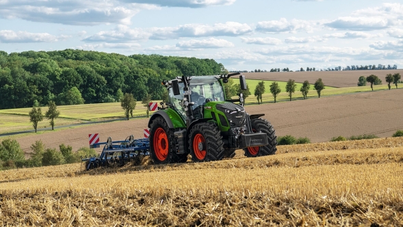 Ein grüner Fendt Traktor mit roten Felgen bei der Bodenbearbeitung auf einem abgeernteten Feld mit sanfter Hügellandschaft im Hintergrund