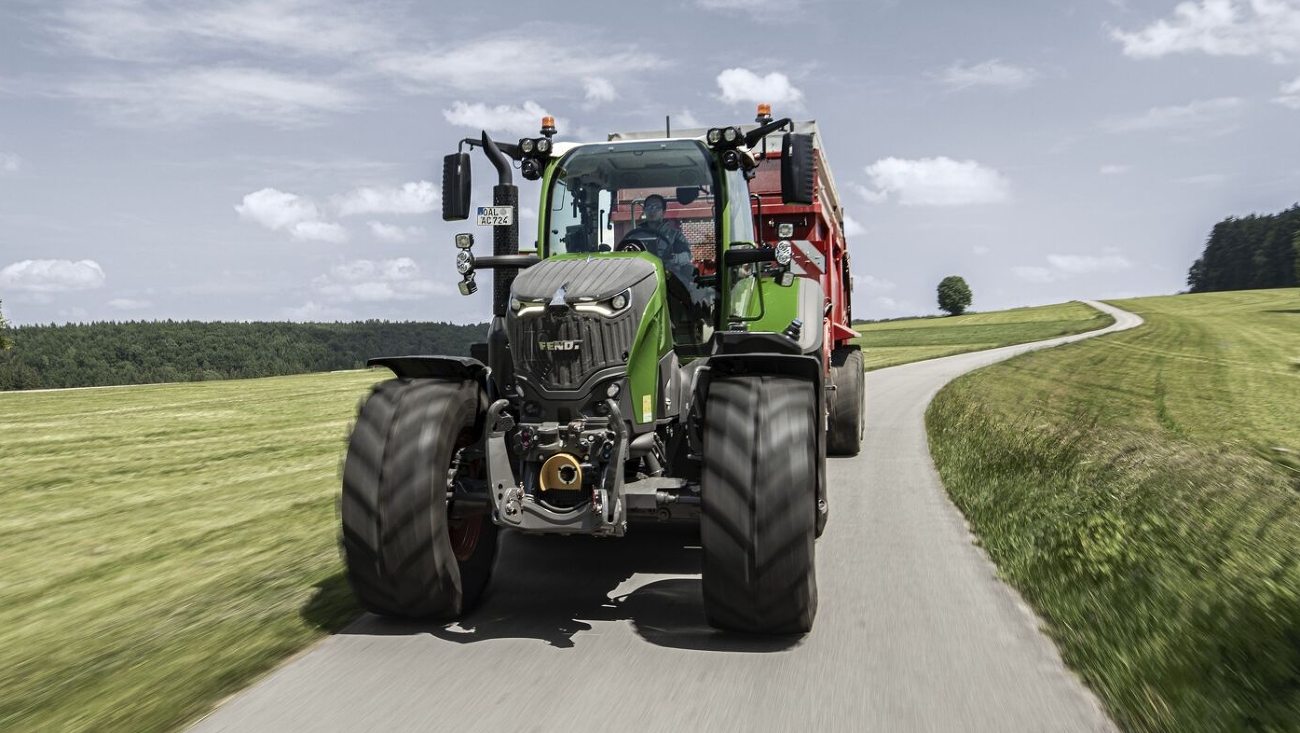 Ein Fendt 700 Vario Gen7.1 mit Ladewagen fährt im Sommer auf einer Landstraße