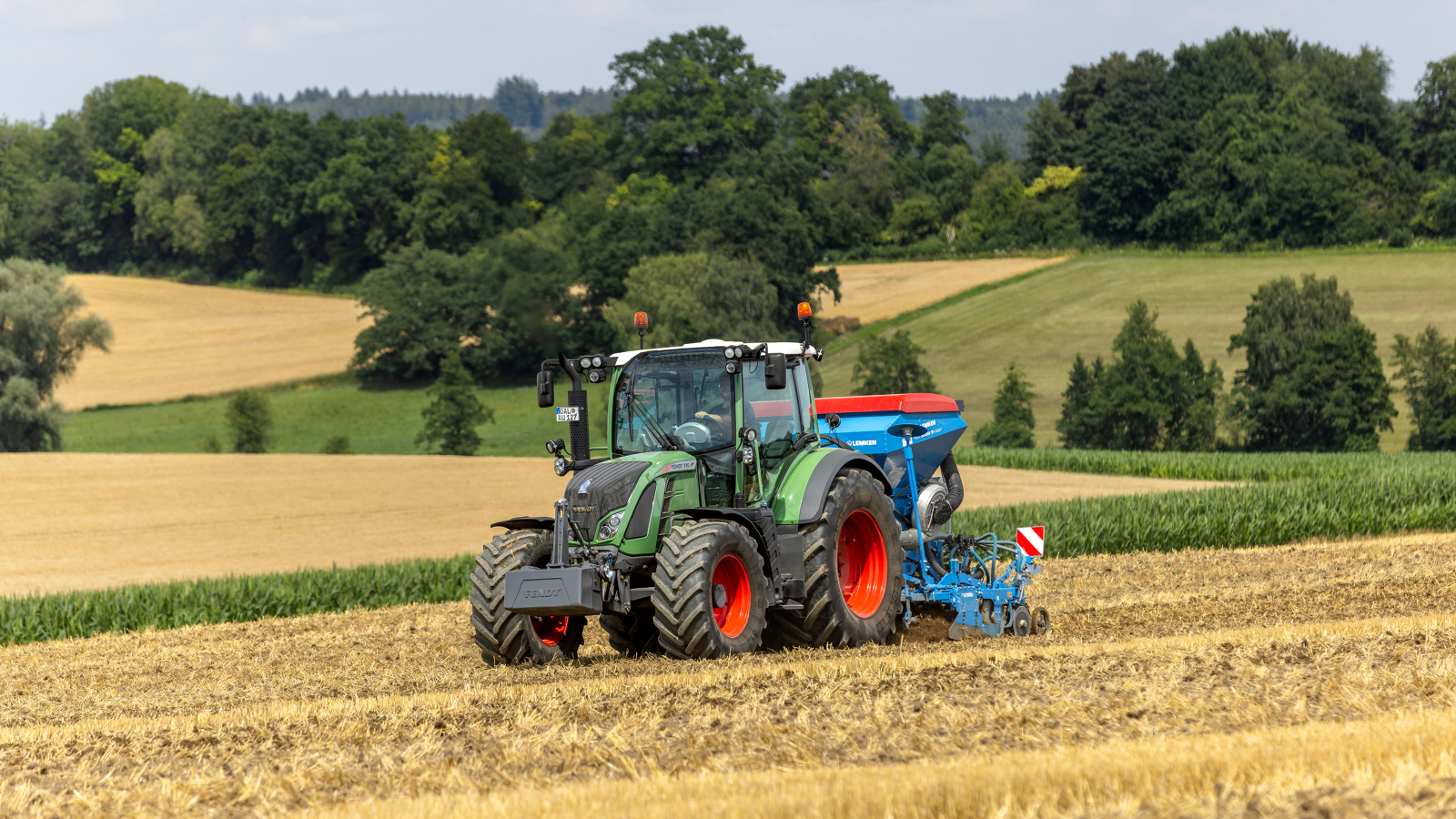 Fendt 500 Vario Ein Landwirt fährt mit einem Fendt 500 Vario auf einem Acker, im Hintergrund ist ein Hügel mit Bäumen zu sehen.