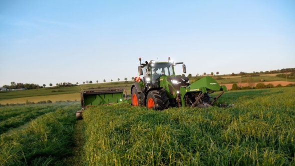Fendt Traktor mit Slicer-Kombination Fendt Traktor mit Slicer-Kombination beim mähen einer grünen Wiese mit blauen Himmel