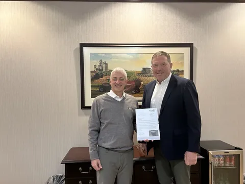 Two men standing in an office, one holding a document.