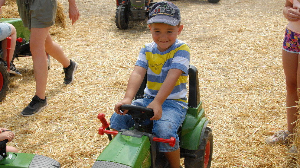 The child is happy to sit on the Fendt pedal tractor