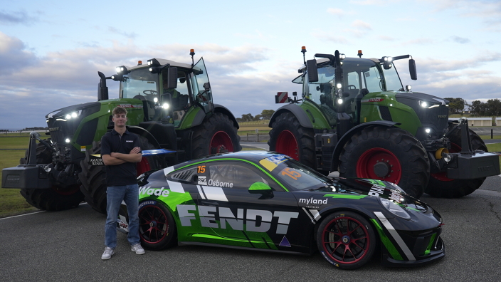 Clay Osborne standing in front of two green Fendt tractors and his Porsche racing car with the Fendt logo