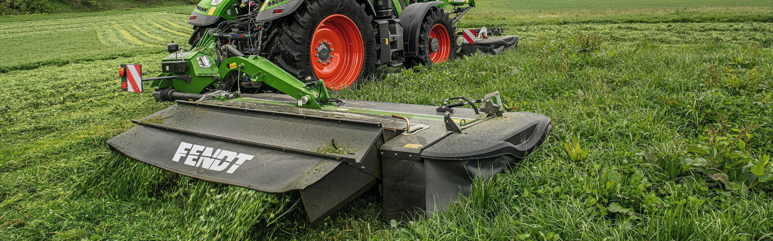 Green harvesting A Fendt 700 Vario with a slicer front-mounted and rear-mounted on the right-hand side in grassland.