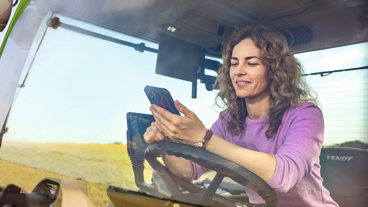 A farmer in a green Fendt tractor uses the Fendt Parts Books to go app