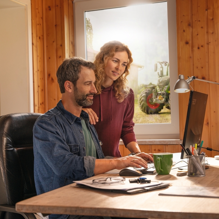 A farmer couple in front of their office computer, creating field boundaries with FendtONE Agronomy.