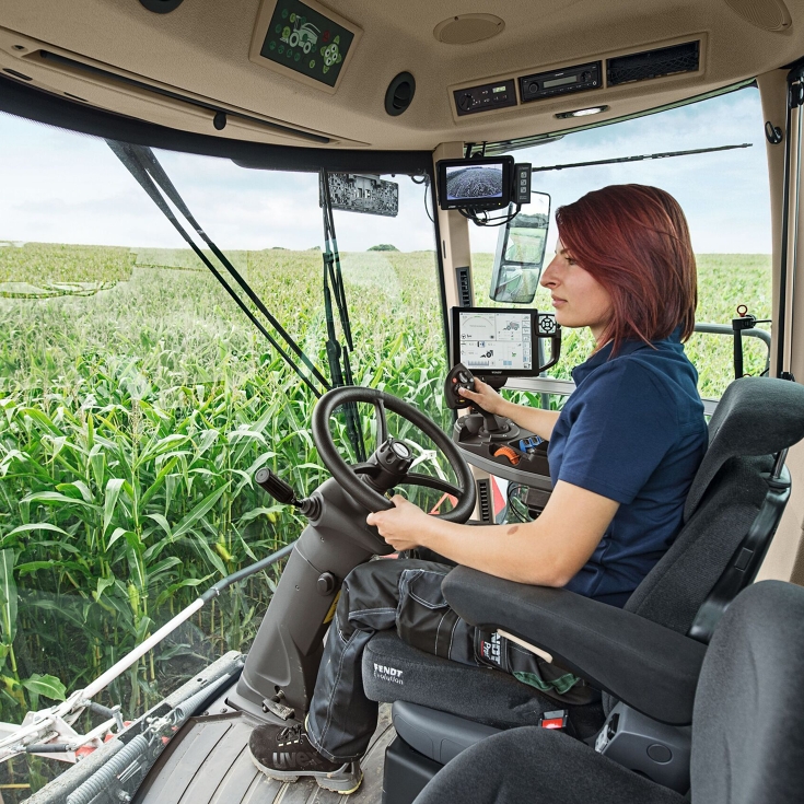 A farmer sits in her Fendt Katana and steers the machine through a maize field.