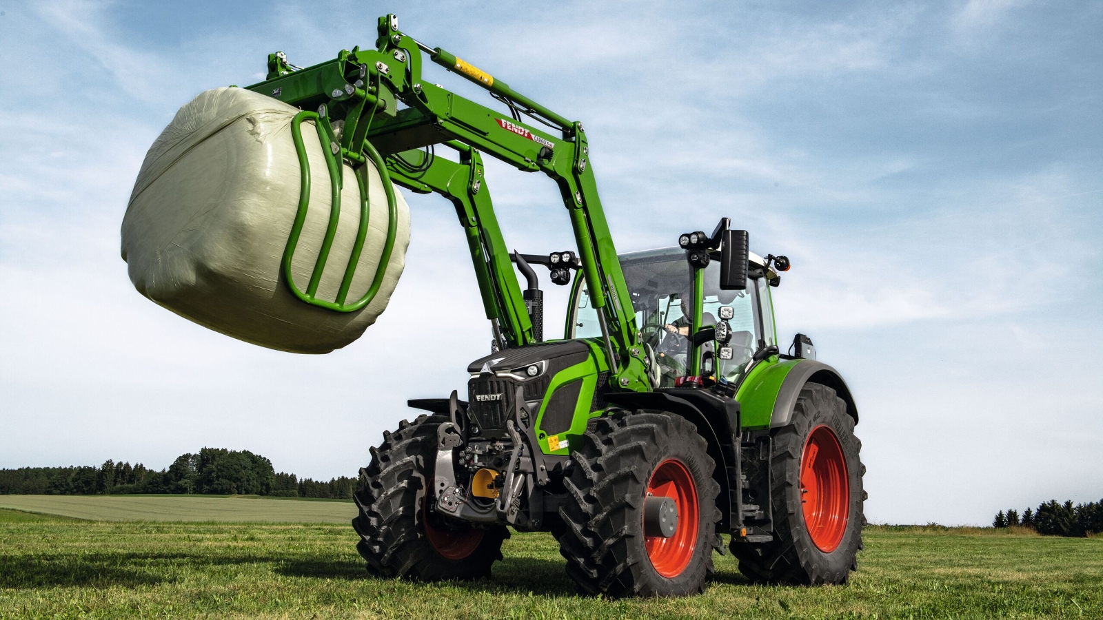 A Fendt 600 Vario using a front loader to grab a silo bale.