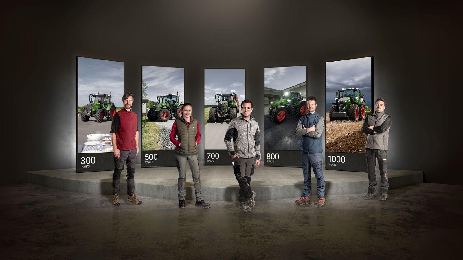 5 people standing next to each other, behind them, large screens with the Fendt 300, 500, 700, 800 and 1000 Vario.