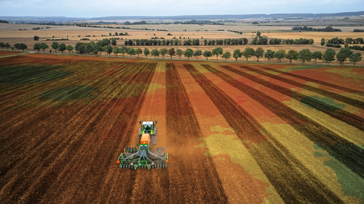 Um trator Fendt verde com acessório para o cultivo preciso do solo graças ao controle da máquina FendtONE