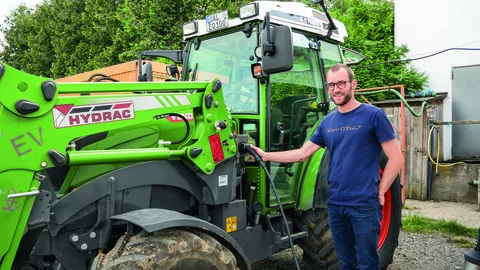 Landwirt lädt den stehenden batteriebetriebenen Fendt e100 Vario mit Frontlader