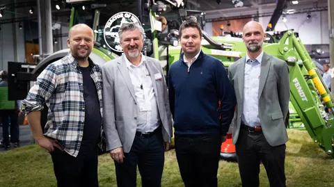 4 Menschen stehen vor einem Fendt Traktor in der Messehalle