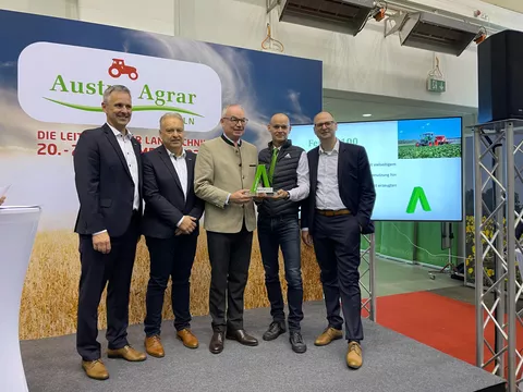 Übergabe des AgrarTec Klimafit 2024 für den Fendt e100 Vario durch Heinrich Prankl an das Fendt Österreich Team mit Georg Herbig, Kurt Wipfler und Eward Snieder sowie Roman Roth von der ACA GmbH, alle Herren stehen auf einer Bühne vor einer Leinwand