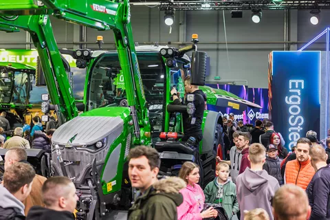 Viele Menschen besuchen den Fendt Stand auf der Agrotech Kielce 2025 und stehen um einen Fendt Traktor mit erhobenem Frontlader