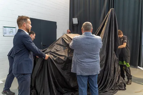 4 Männer ziehen an einem schwarzen Tuch, darunter die Fendt Zapfanlage