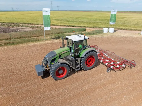 ein grüner Fendt 942 Vario mit Ovlac-Grubber und Walze auf einem Feld im Hintergrund zwei Fendt Fahnen