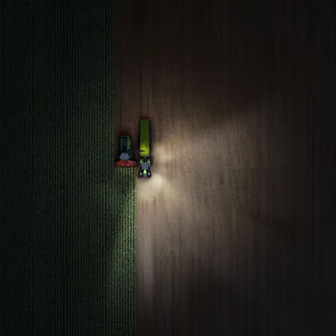 Drohnenaufnahme von einem Fendt 800 Vario in der Nacht mit eingeschalteten Lichtern - links.