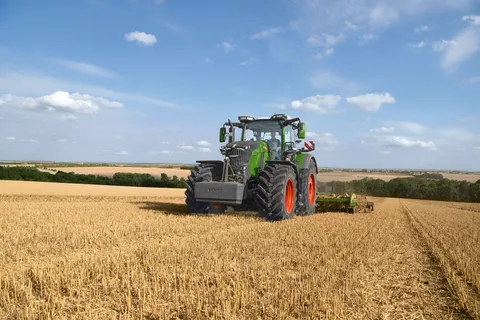 Ein grüner Fendt 800 Vario bearbeitet mit einer Scheibenegge von Amazone in grüne-orange ein Stoppelfeld.