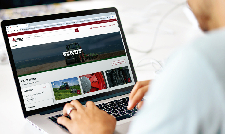 Ein Mann sitzt vor einen Laptop und schaut sich eine Website an. Der Mann ist nur von hinten zu sehen und ist leicht unscharf. Im Laptop ist eine Website zu sehen, die Bilder zum Donwload anbietet.
