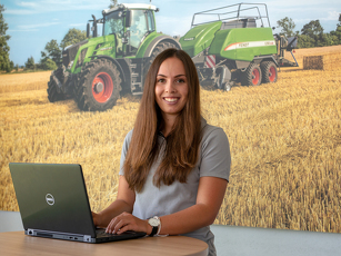 Fendt Mitarbeiterin steht an einem Stehtisch und tippt in ihren Laptop