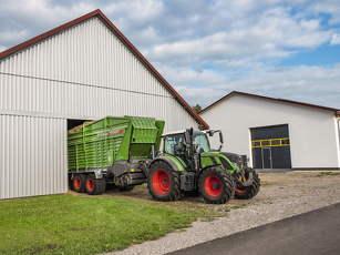 Fendt Tigo Ladewagen mit Fendt Traktor beim Entladen in eine Halle