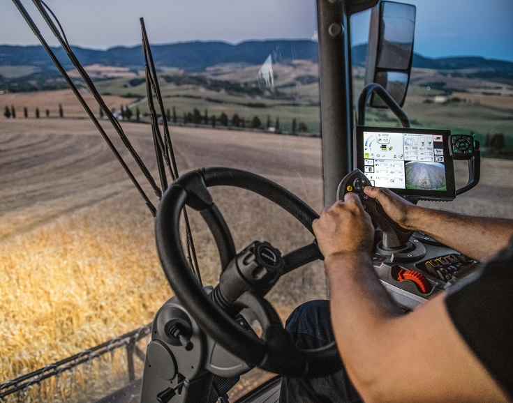 In der Kabine des Fendt C SL sitzt ein Mann am Lenkrad und bedient den Joystick an seiner Armlehne, neben dem 10.4" Terminal.