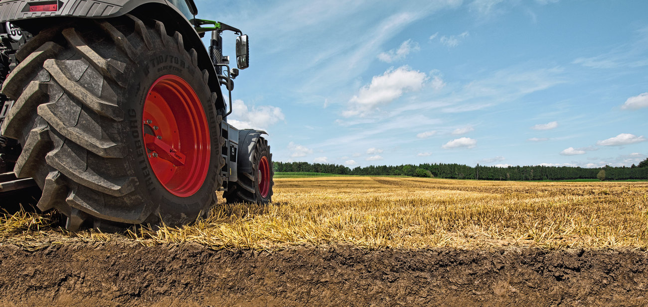 Fendt 900 Vario mit integrierter Reifendruckregelanlage Fendt VarioGrip steht auf  einem Acker. Im Vordergrund ist ein Querschnitt des Bodens zusehen.