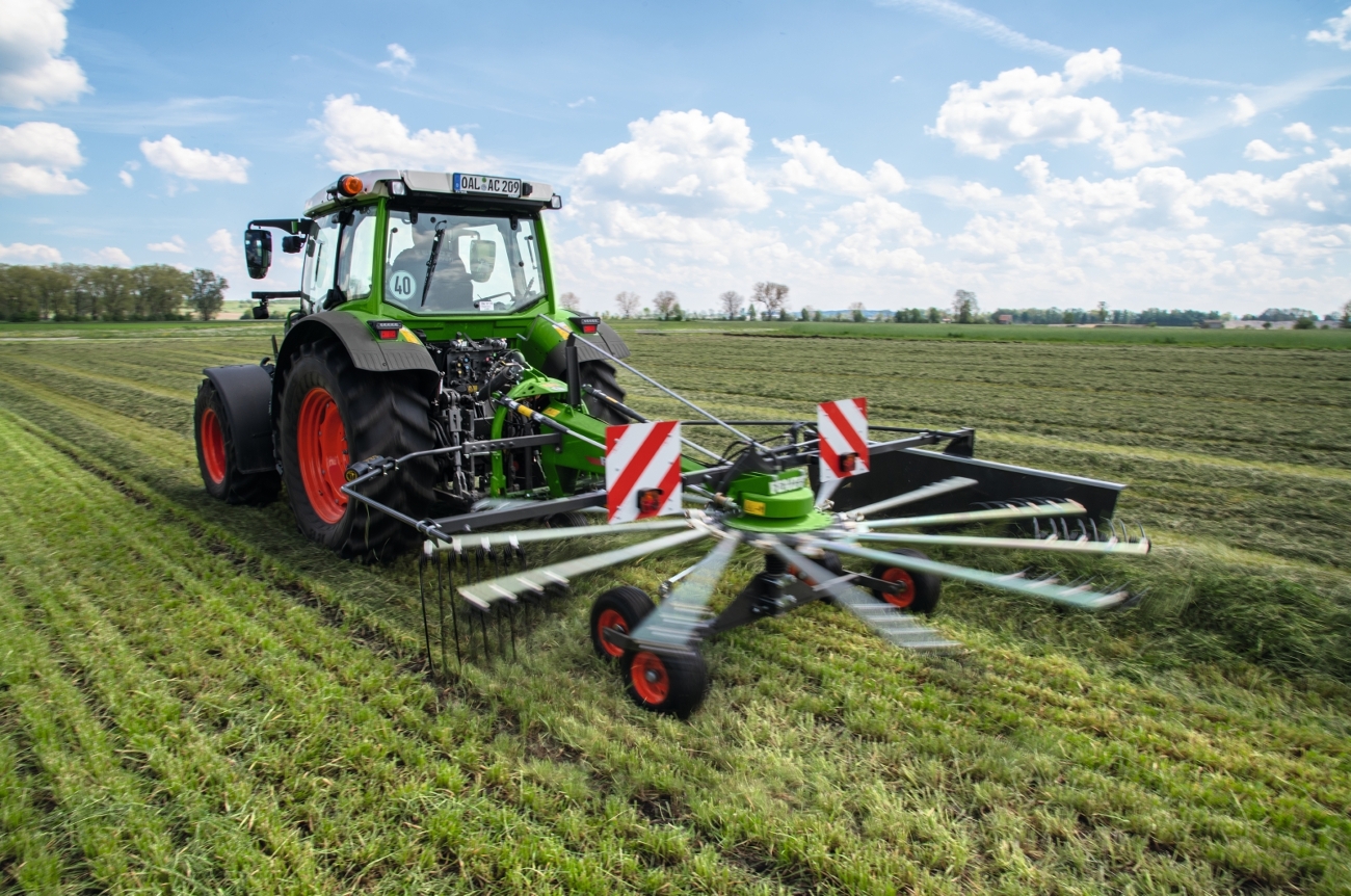 Fendt 200 Vario Traktor mit Fendt Former Einkreiselschwader auf einer Wiese