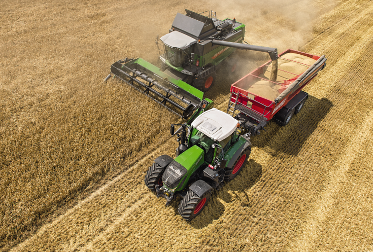 Fendt L-Serie Korntankentleerung Der Mähdrescher der L-Serie entleert seinen Korntank in den Ladewagen neben ihm, der von einem Fendt Vario gezogen wird.